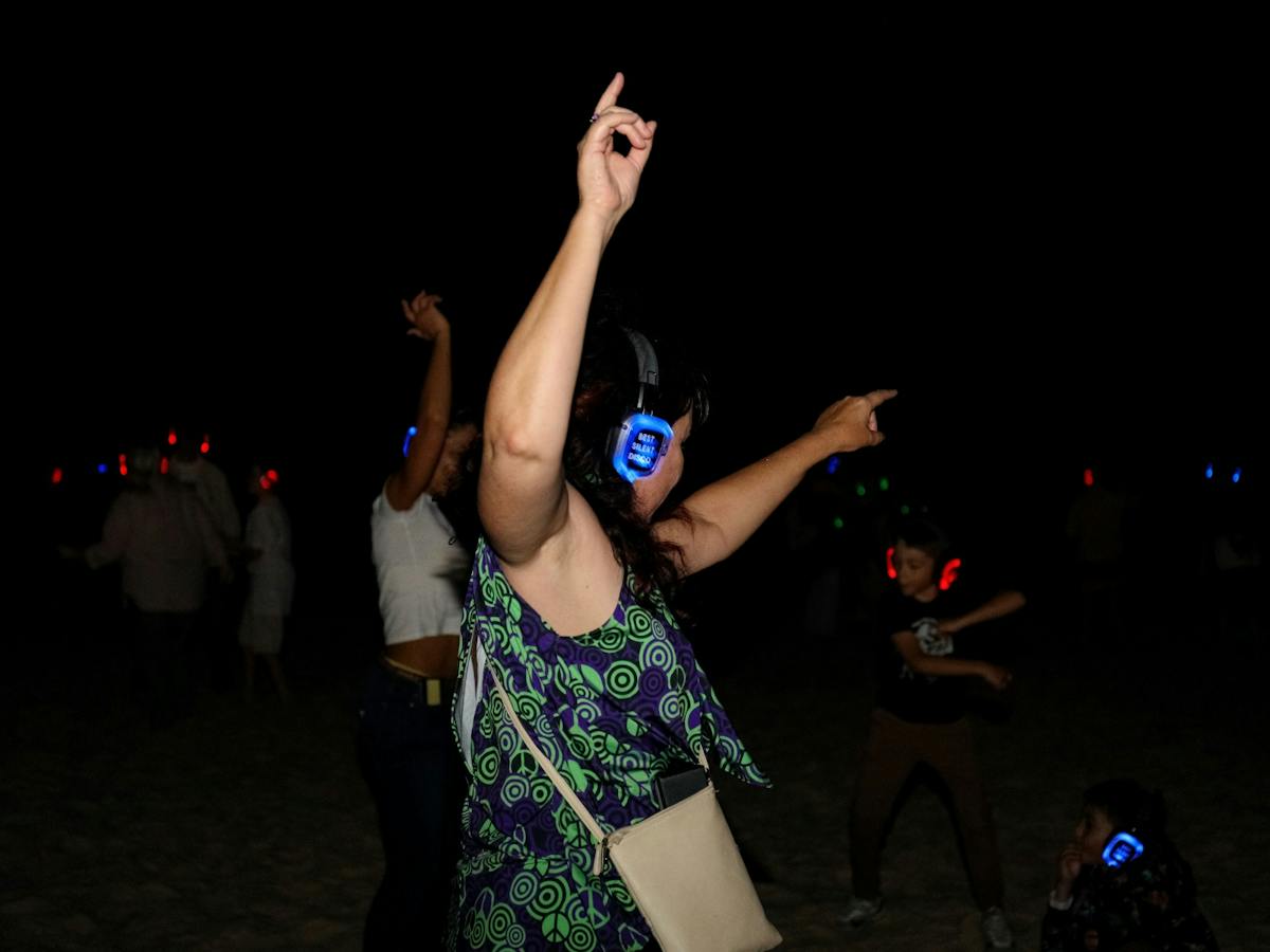 100's of people dancing on the beach atSilent Disco Under the Stars at SWELL Sculpture Festival 2024