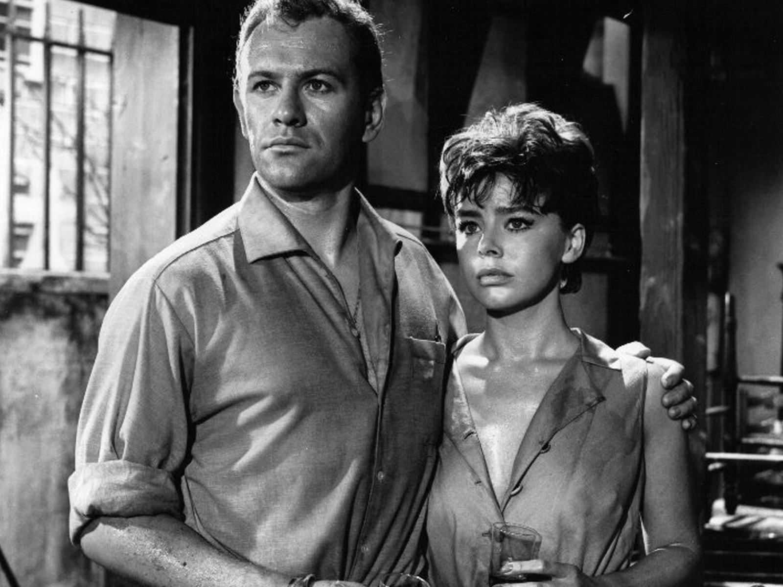 Black and white image of woman and man standing together looking forlorn past the camera