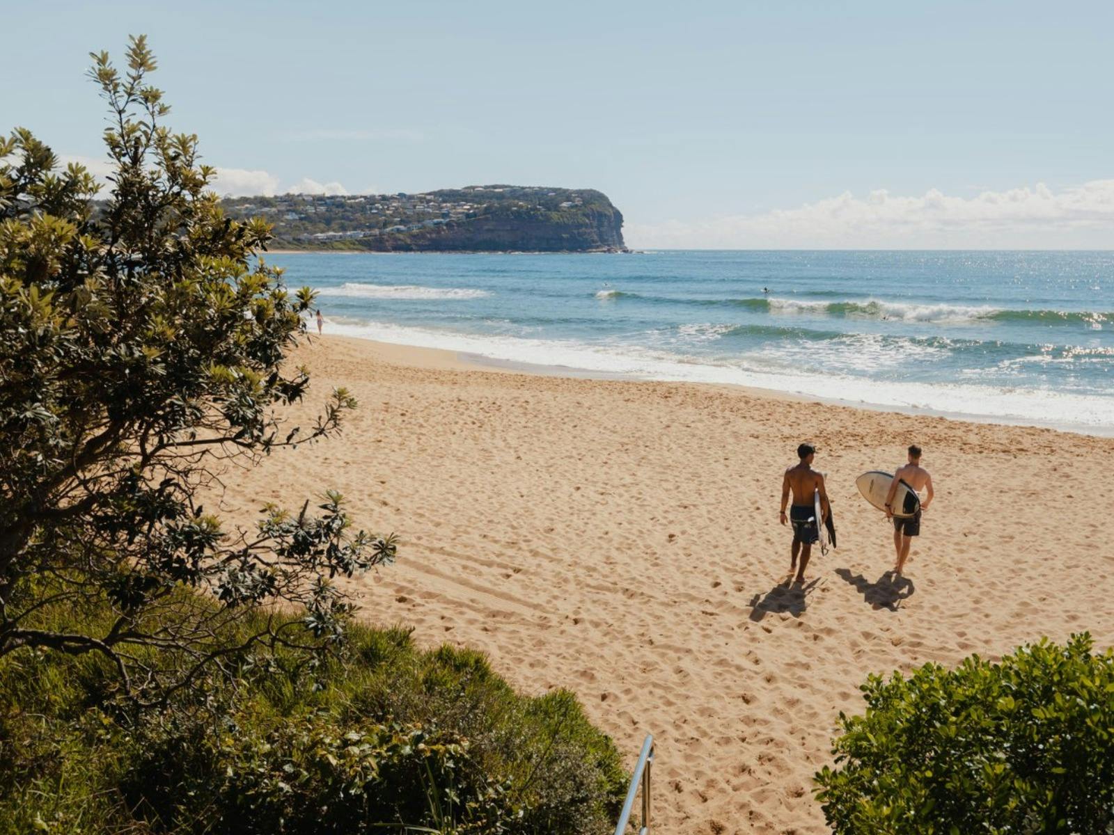 Two surfers carrying surfboards towards the ocean