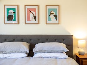 bed with three pictures of Kookaburras each with a coloured background and a lamp on a bedside table