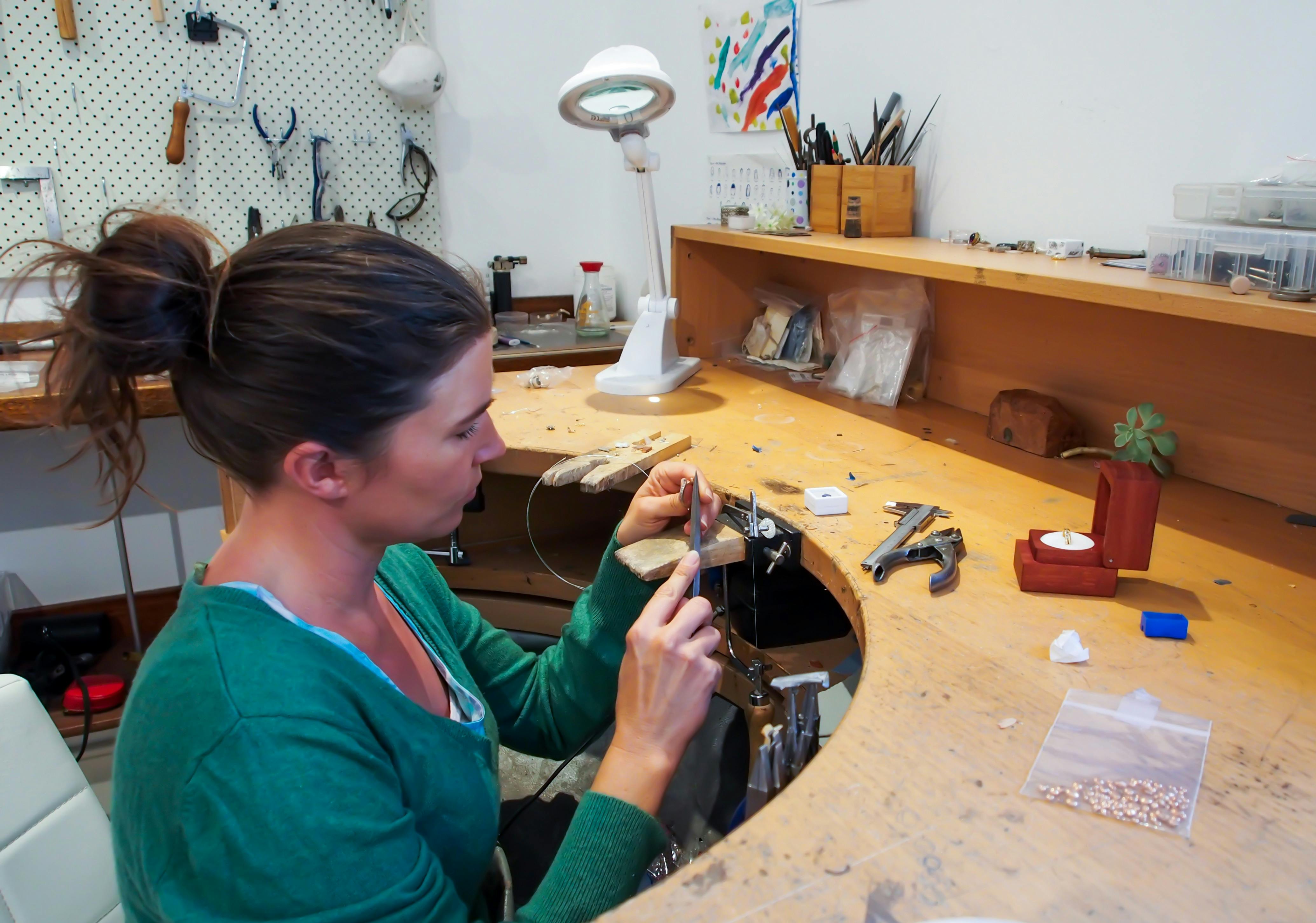 珠宝商佐伊·普克坐在她的珠宝工作台前，正在制作一件珠宝。