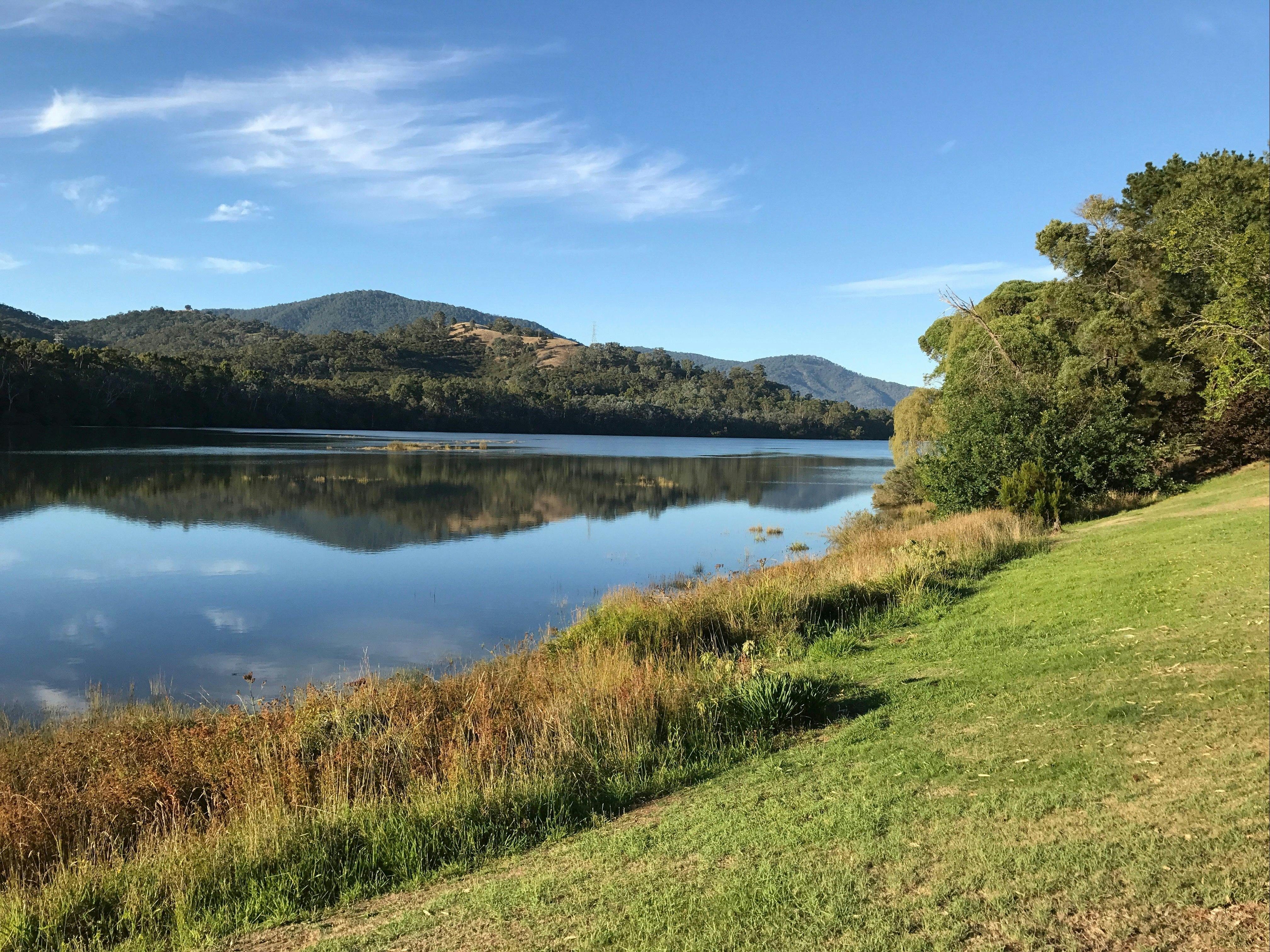 Lake with green grass on the outside and hills in the background