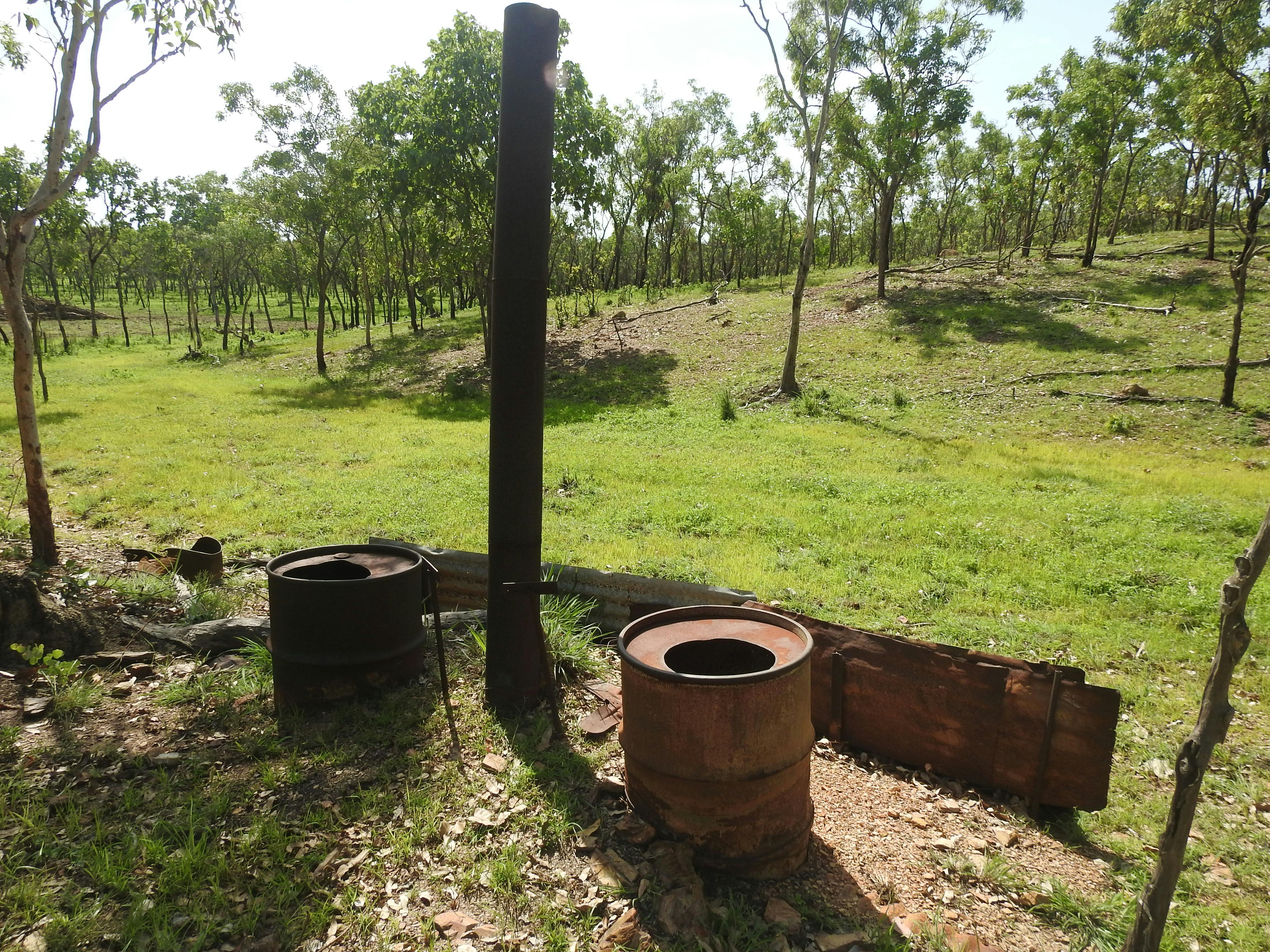 44 gallon drums sit beside a pipe chimney overlooking green pasture
