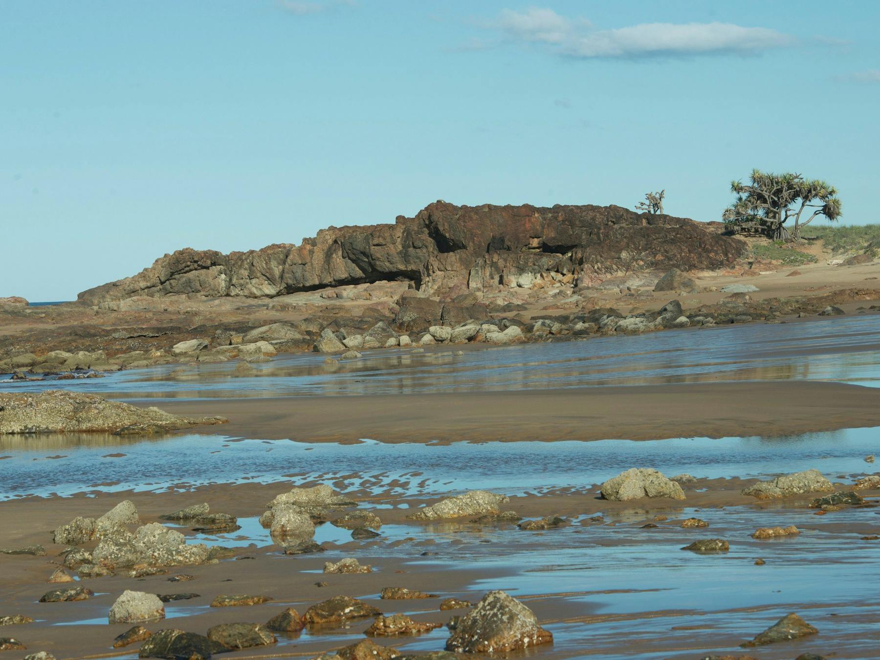 Two people on Wreck Rock Beach walking among volcanic rock pools , Deepwater National Park