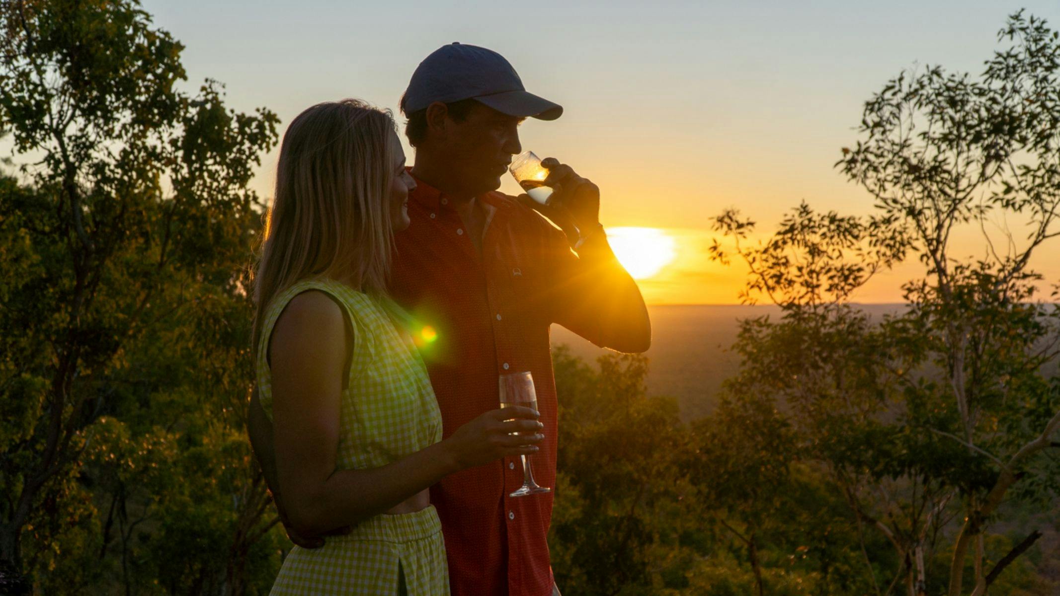 A couple enjoying the sunset with drinks on remote escarpment.