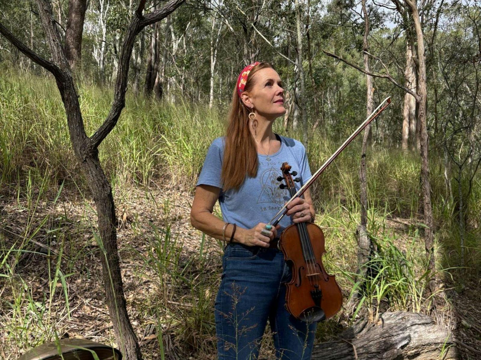 Woman holding a violin in the bush