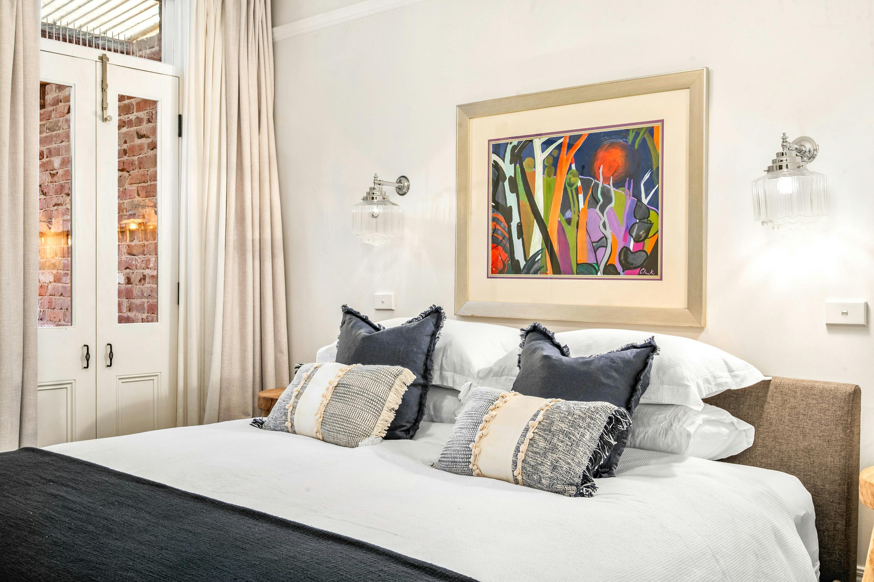 queen bed, grey quilt, beige curtains, abstract artwork, french doors, terrace