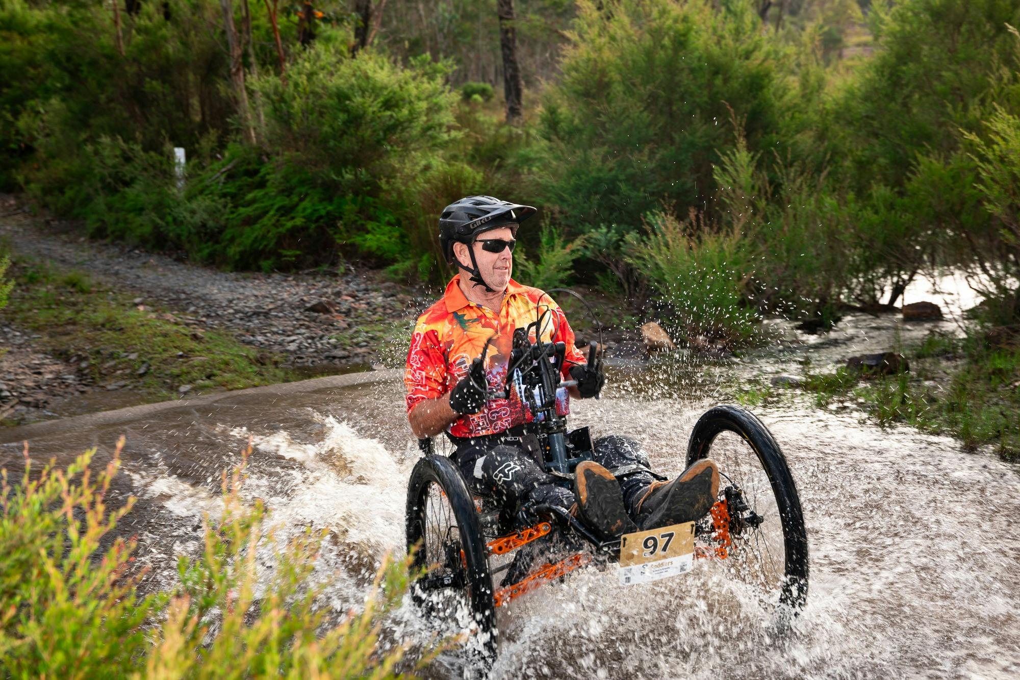 Adaptive rider on a hand cycle crosses water crossing