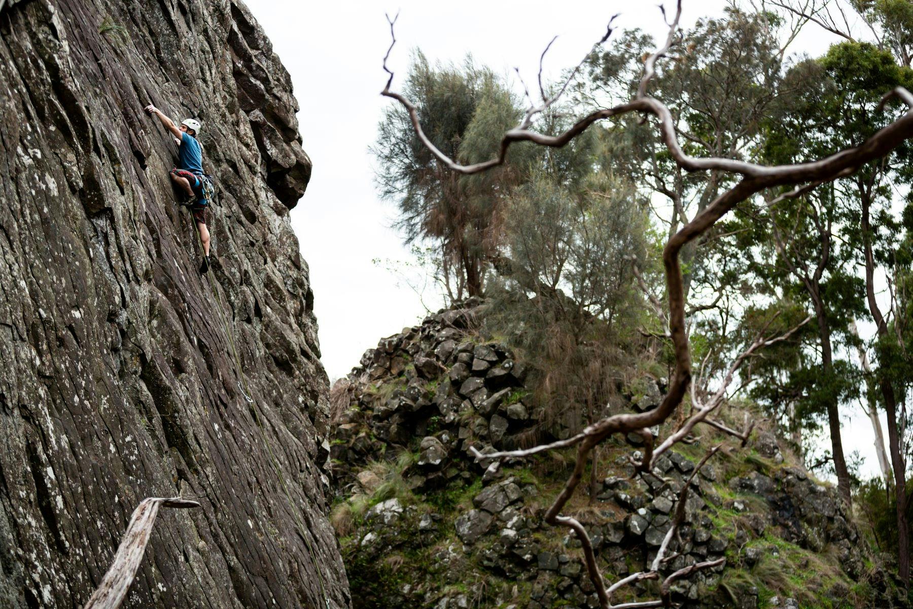 A sheer rock face with a climber scaling it with equipment.