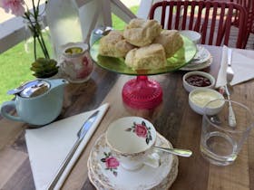 Tea cups and saucers, scones, jam, cream,  on table setting