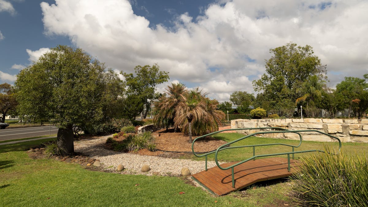 A park with a small wooden bridge and different plants