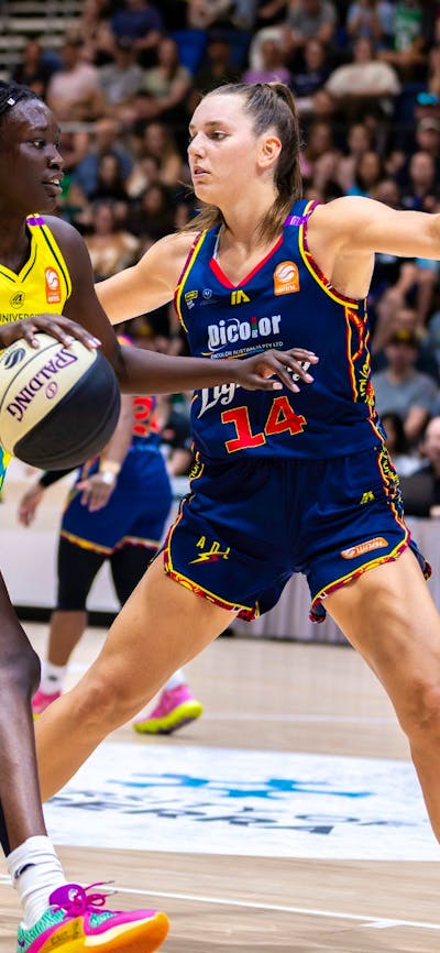 UC Capitals player driving to the basket for a layup during a WNBL game against Adelaide Lightning.