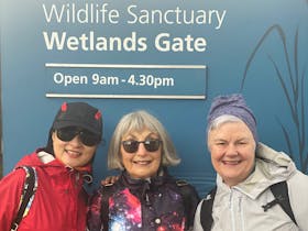 Three women standing at the Wetland Gate about to start a walk