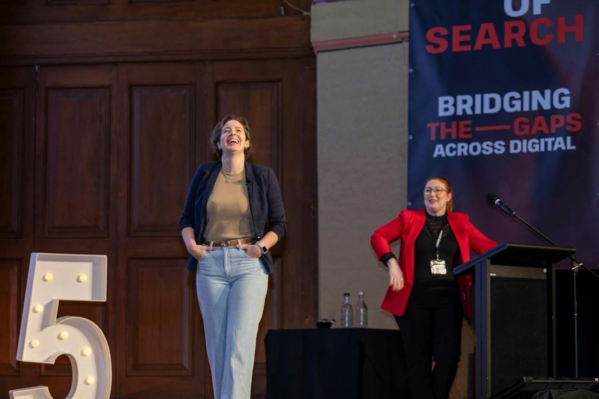 Two women on stage laughing.