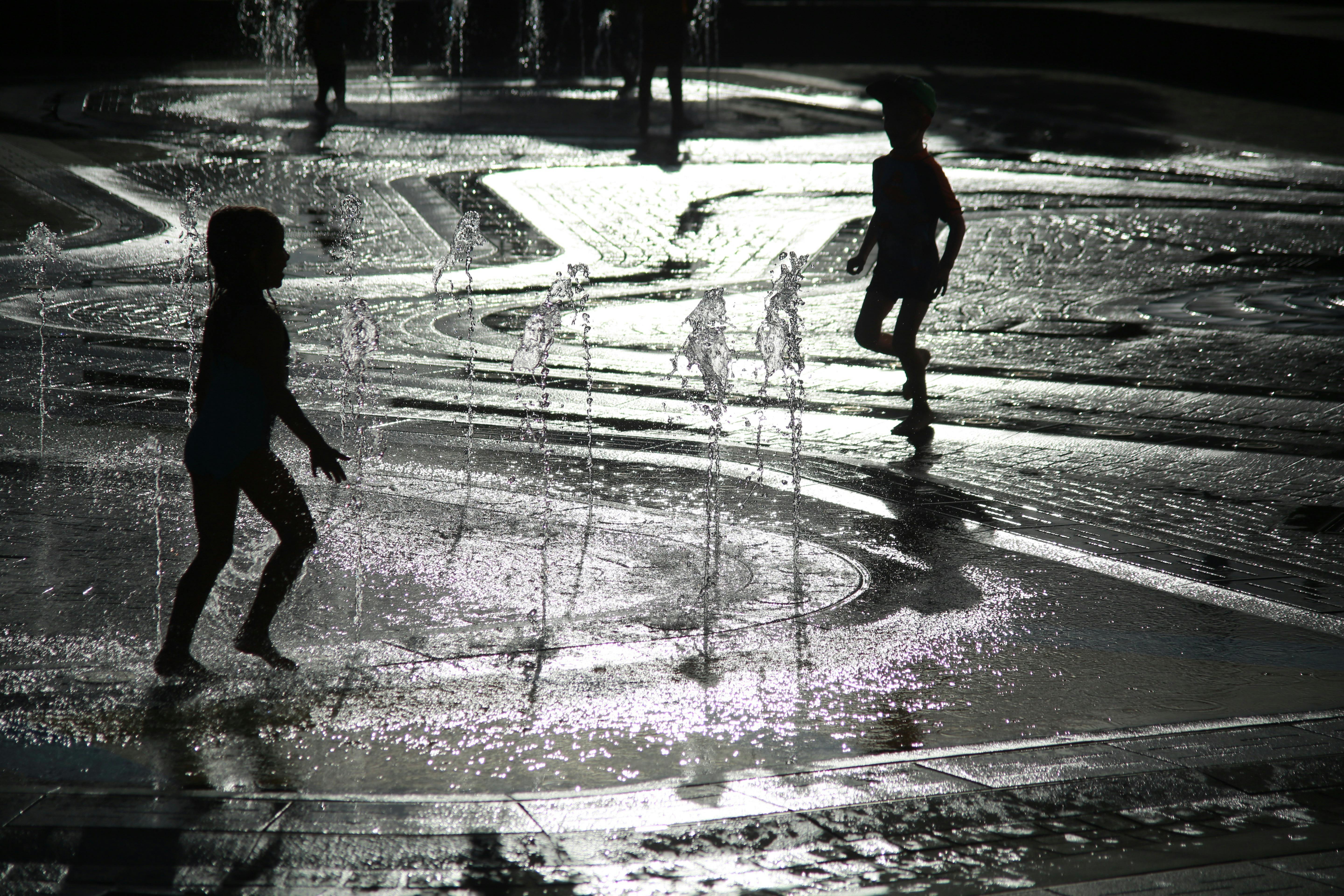 Children silhouetted against summer sun as they play in a water park
