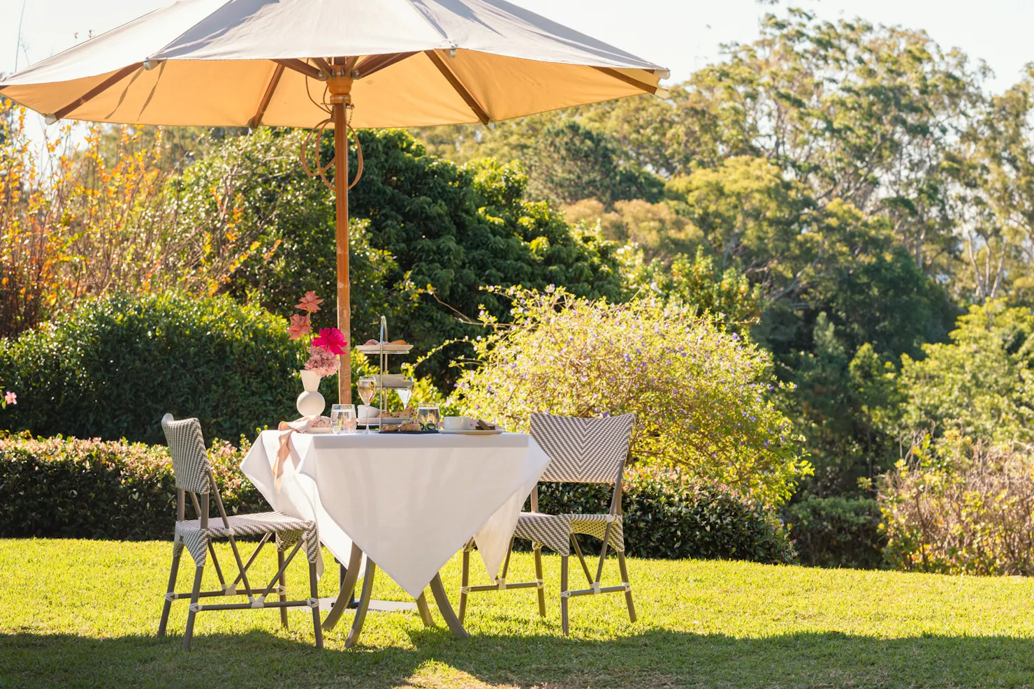 Two chairs and a table in the garden under a big umbrella