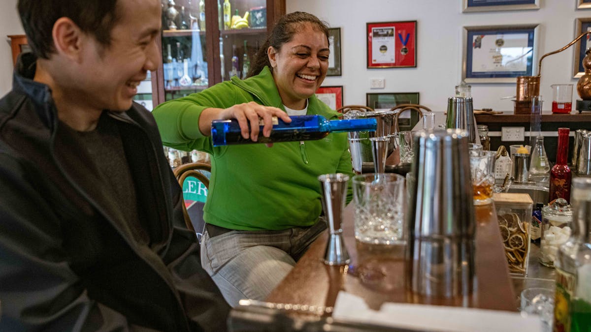 couple pouring liquor into a glass to make a cocktail