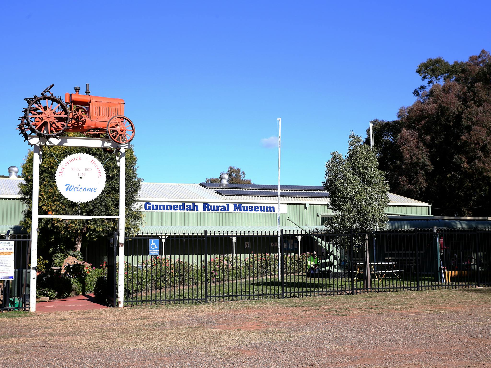 entry gate with tractor mounted on top and the museum building in the background