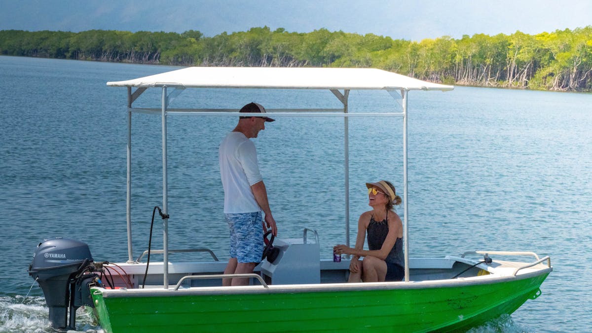 Man and woman sit in a Cairns Boat Hire Tinny heading out for a day on the water Tropical Queensland