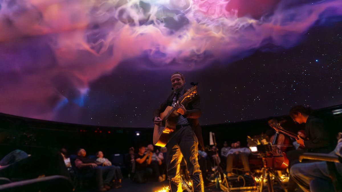 2023 album launch show. A low angle shot of Nate with the band and a nebula behind