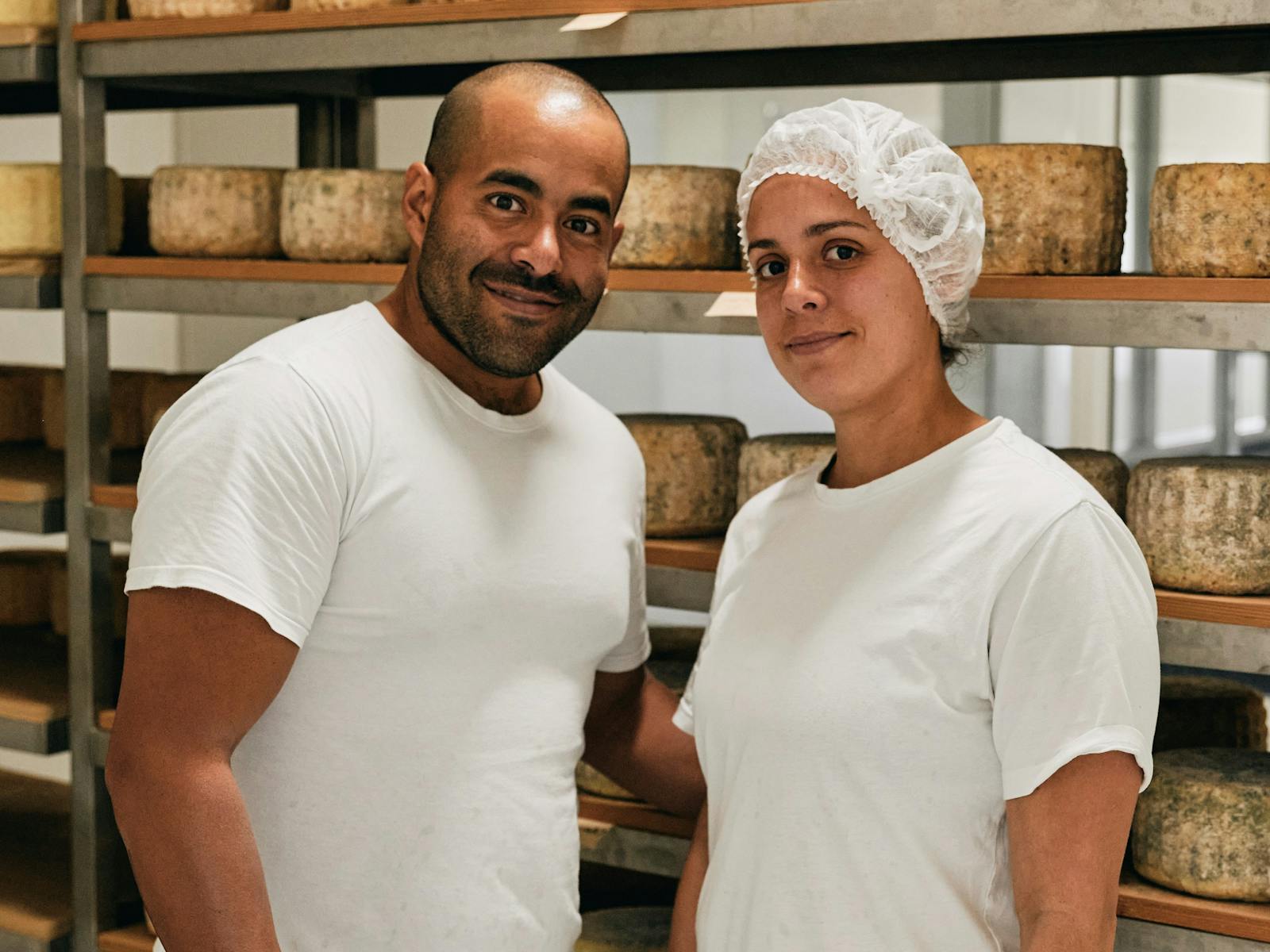 Rosselyn and Genaro the cheese makers standing in front of shelves of cheese.