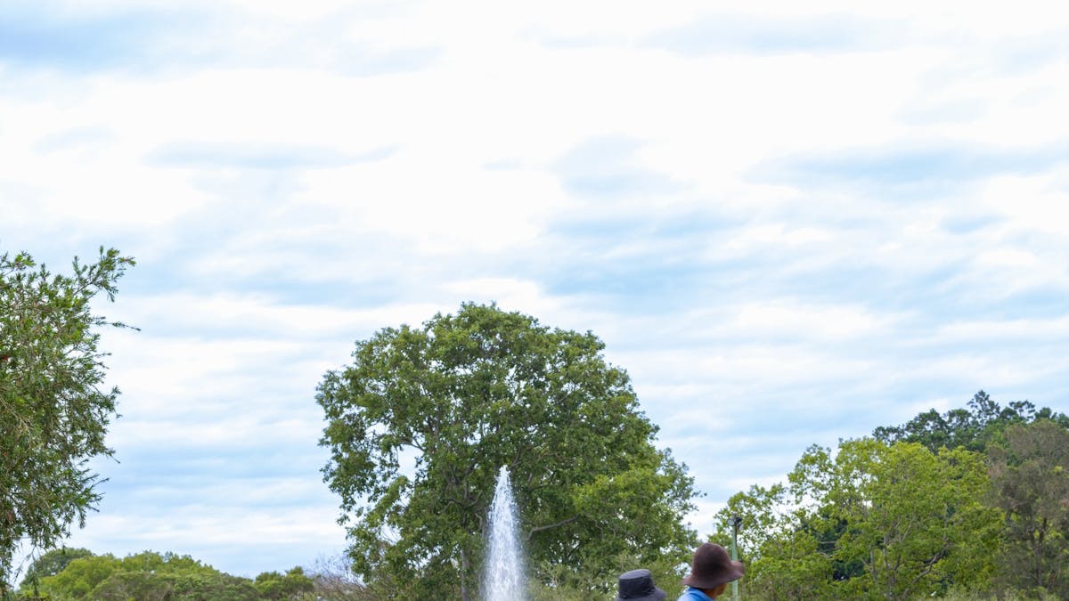 A couple taking a stroll around the pond with the fountain in the background A couple taking a stroll around the pond with the fountain in the background