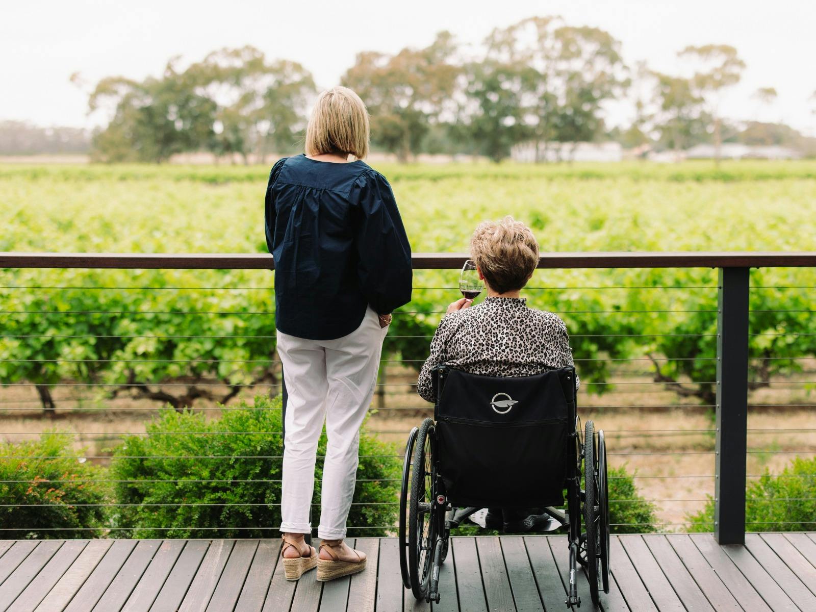 Mum in wheelchair with daughter looking at the view of the grape vinesfrom the front deck