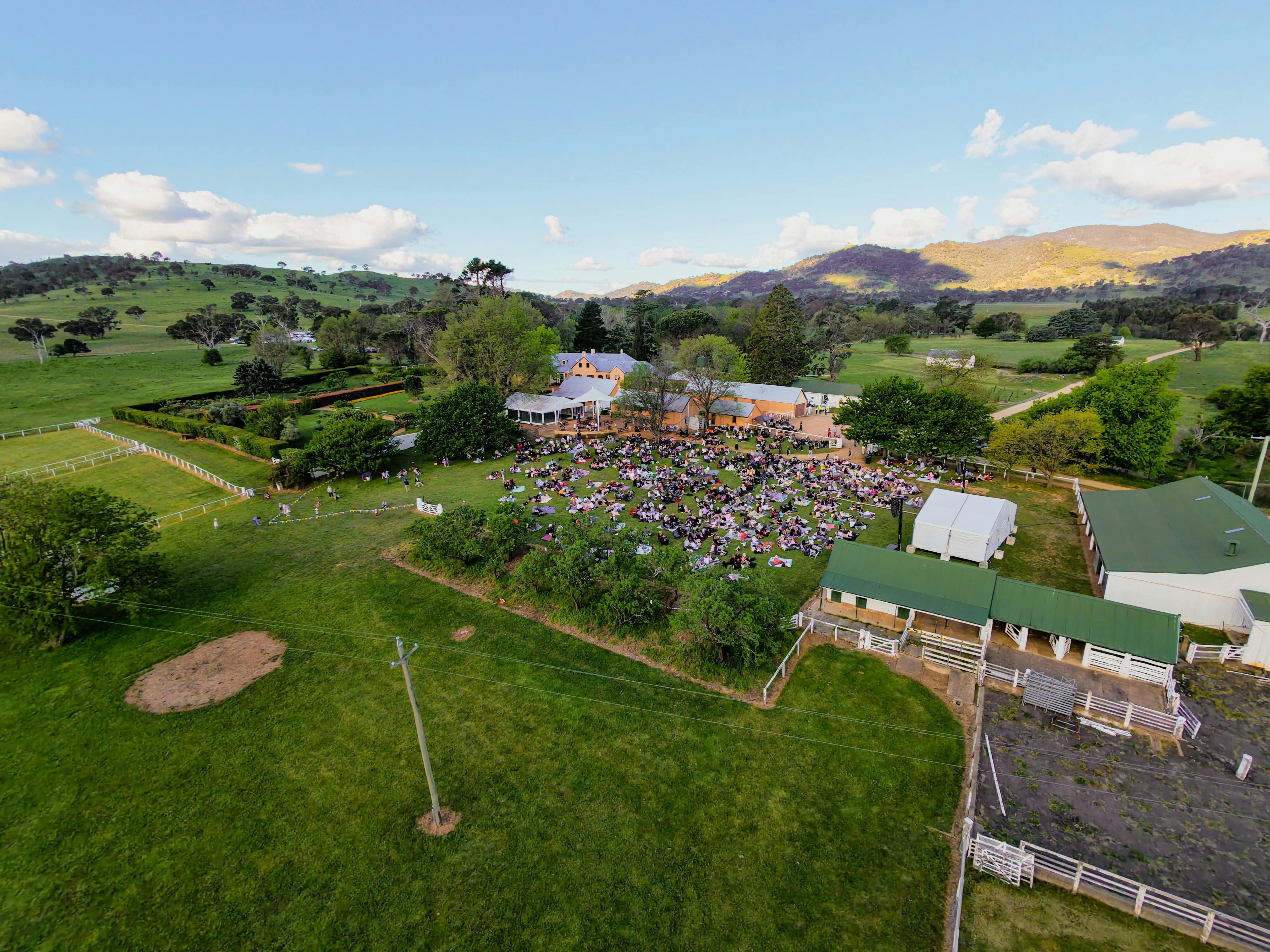 Drone image of Lanyon Homestead with crowd watching concert and buildings in background