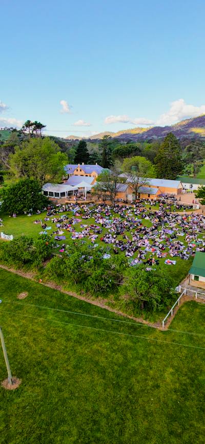 Drone image of Lanyon Homestead with crowd watching concert and buildings in background