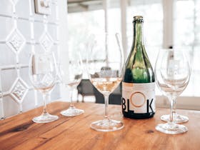 Glasses and an empty sparkling bottle on a timber bench