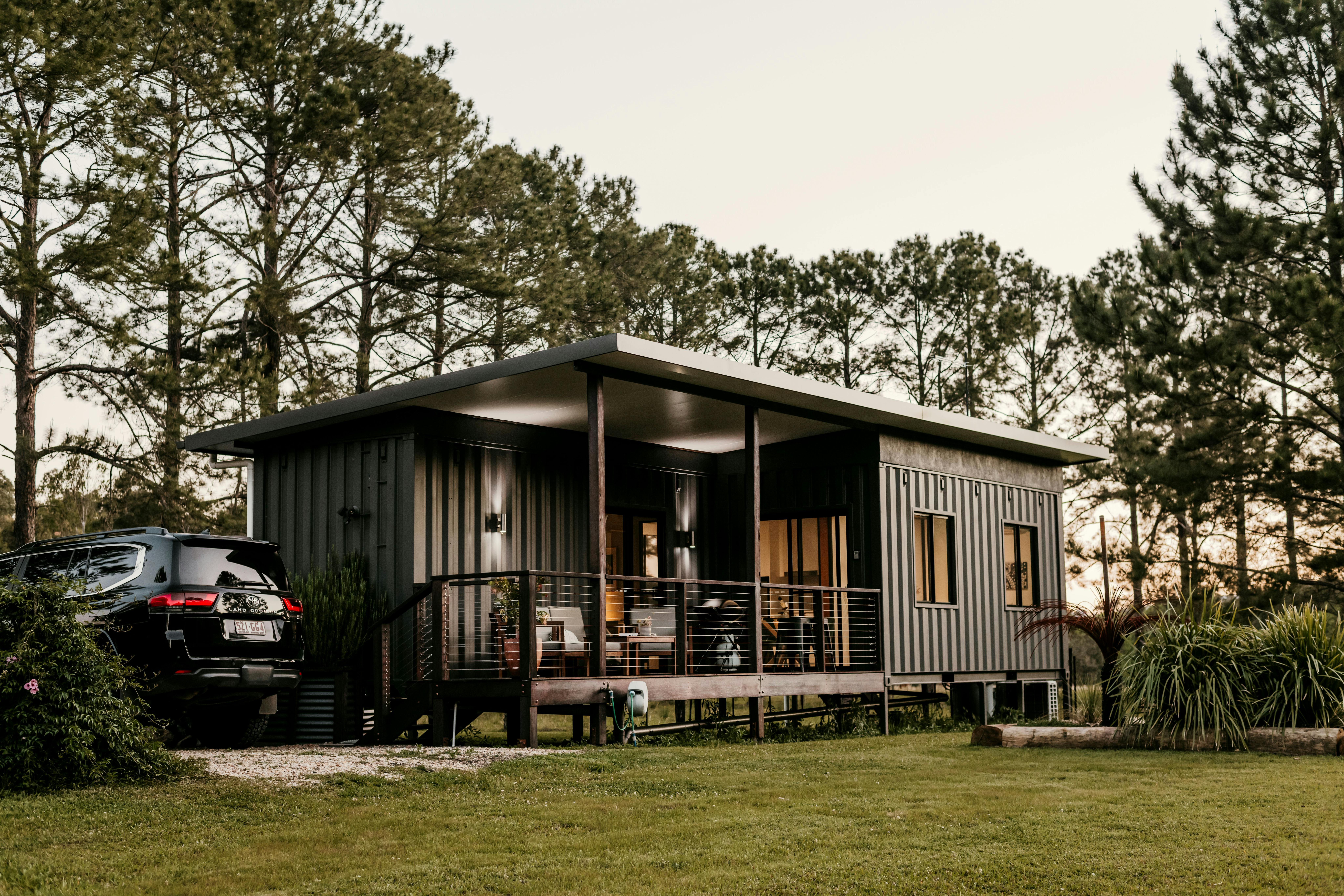 Eco cabin built from shipping containers, set among pine trees at sunset in Nimbin, Australia.