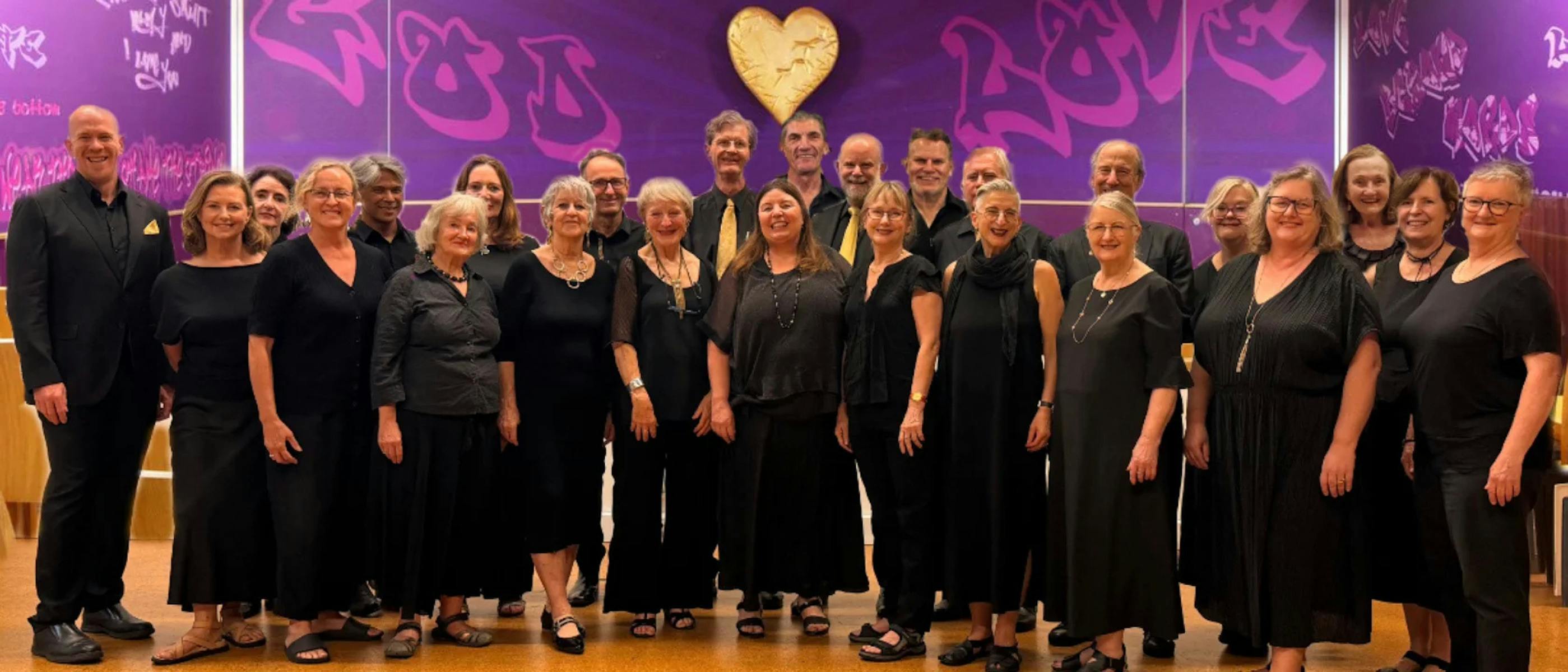A group of singers wearing black stand in front of a purple wall