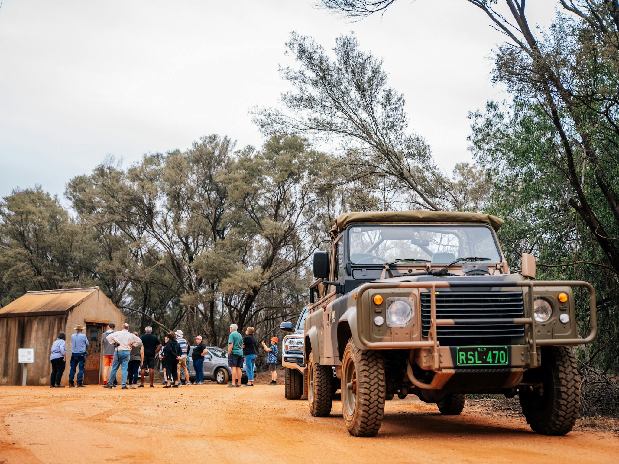 A group of tourists listening to a guide in the background with a military vehicle in the foreground A group of tourists listening to a guide in the background with a military vehicle in the foreground