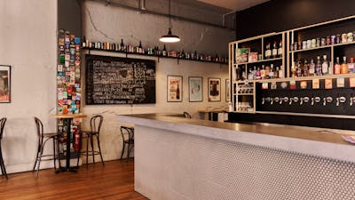 Bar with beer taps behind on the wall and bar tables against opposite wall