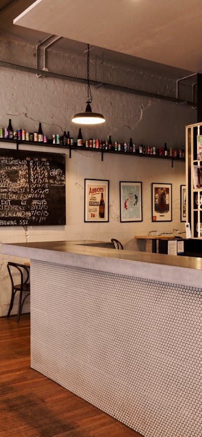 Bar with beer taps behind on the wall and bar tables against opposite wall