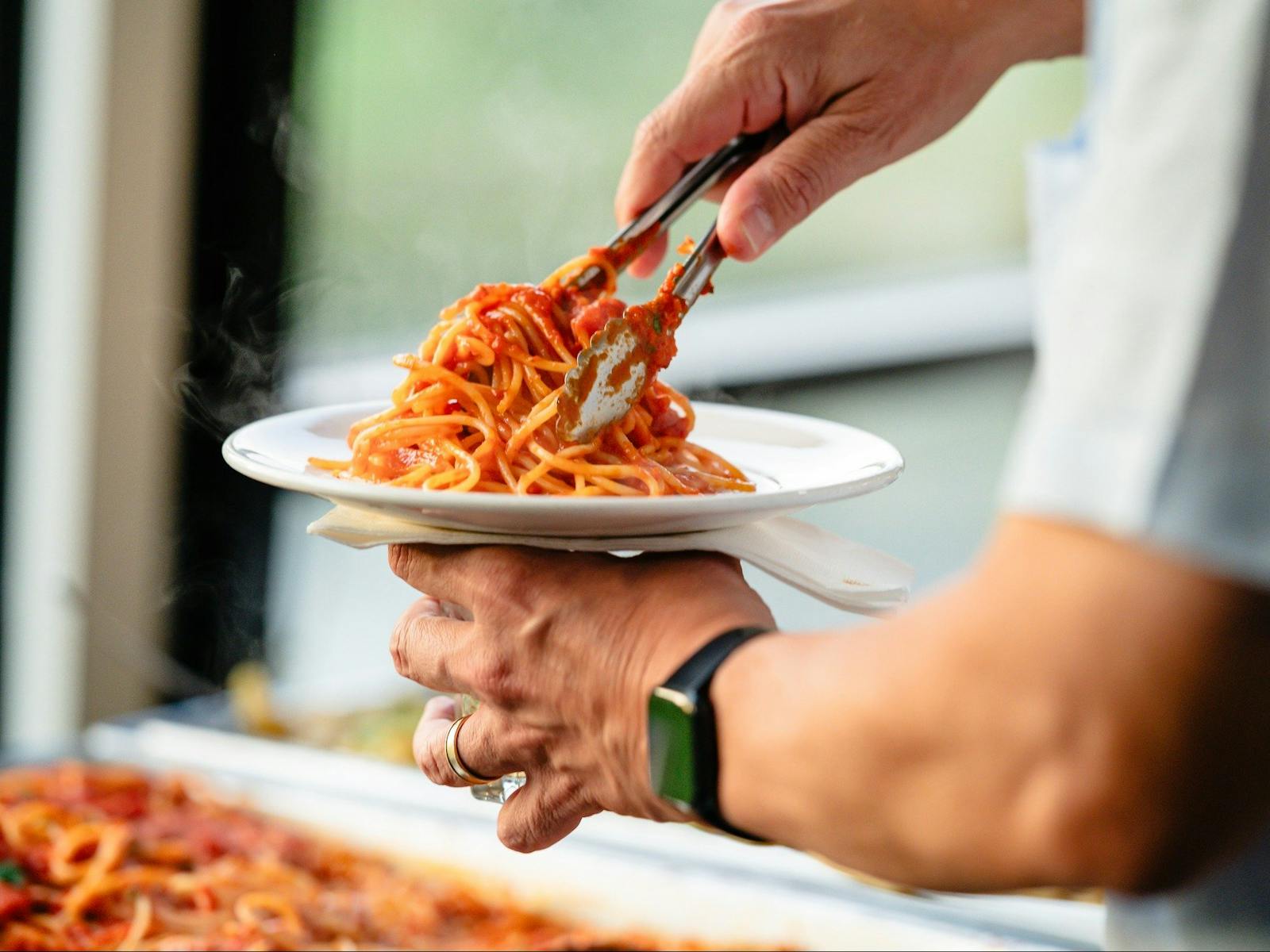 Chef twirling Spaghetti with a red sauce on plate to serve.