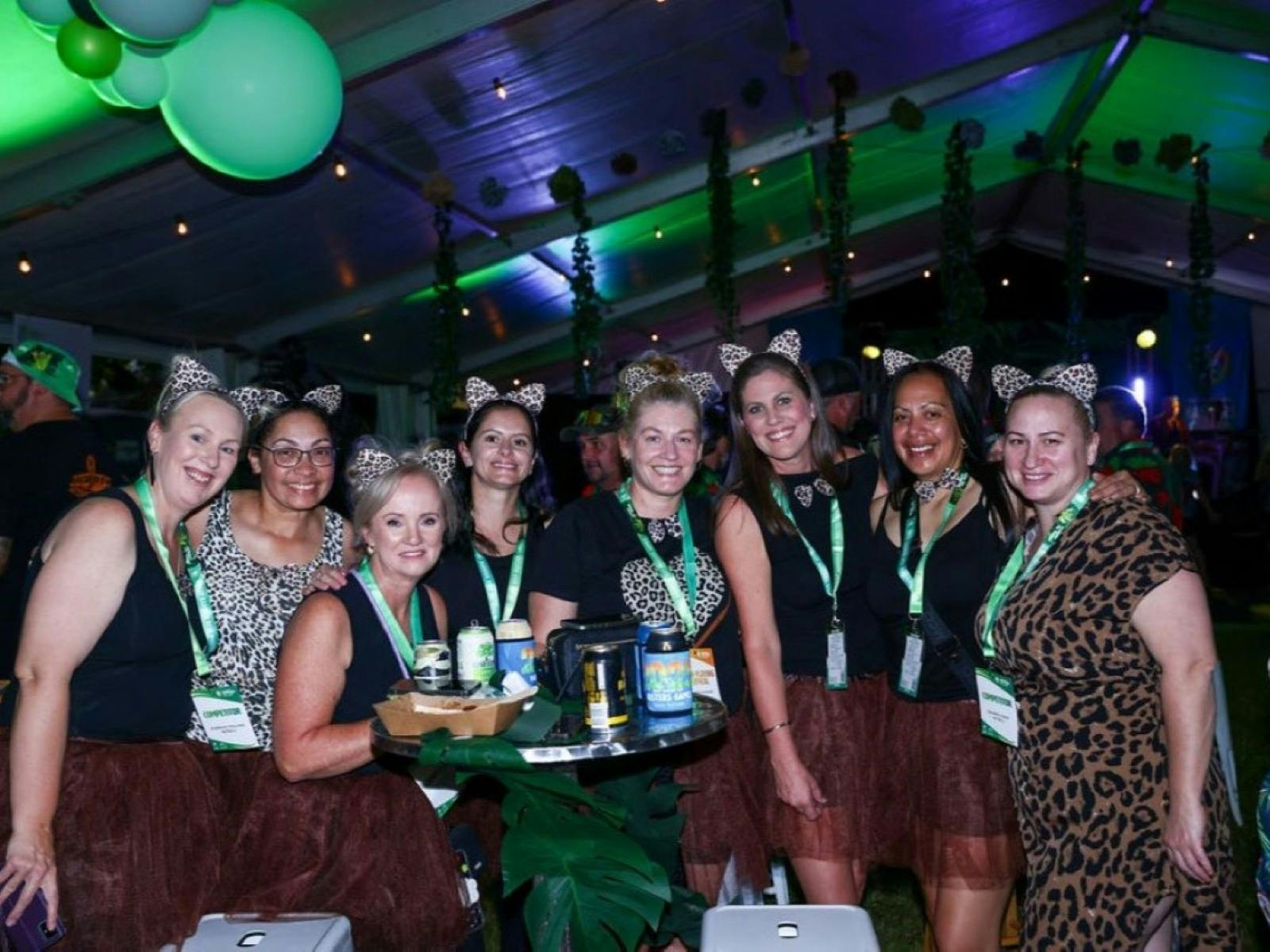 Group of women wearing leopard-print pose together at a Masters festive indoor event