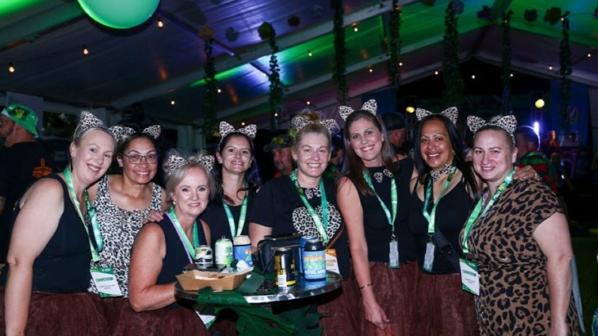 Group of women wearing leopard-print pose together at a Masters festive indoor event