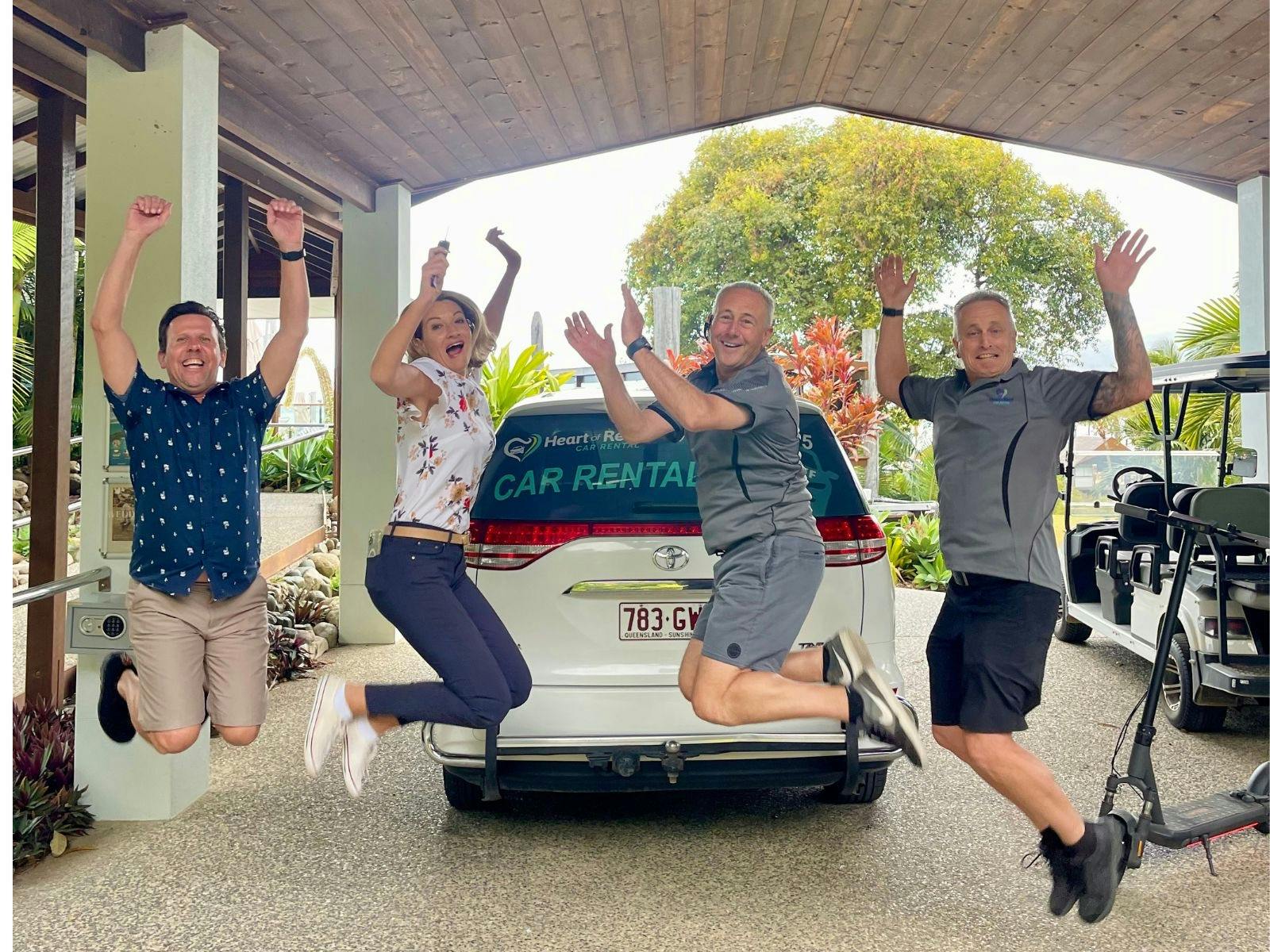 Heart of Reef Car Rental Team and customers jumping in front of car hire
