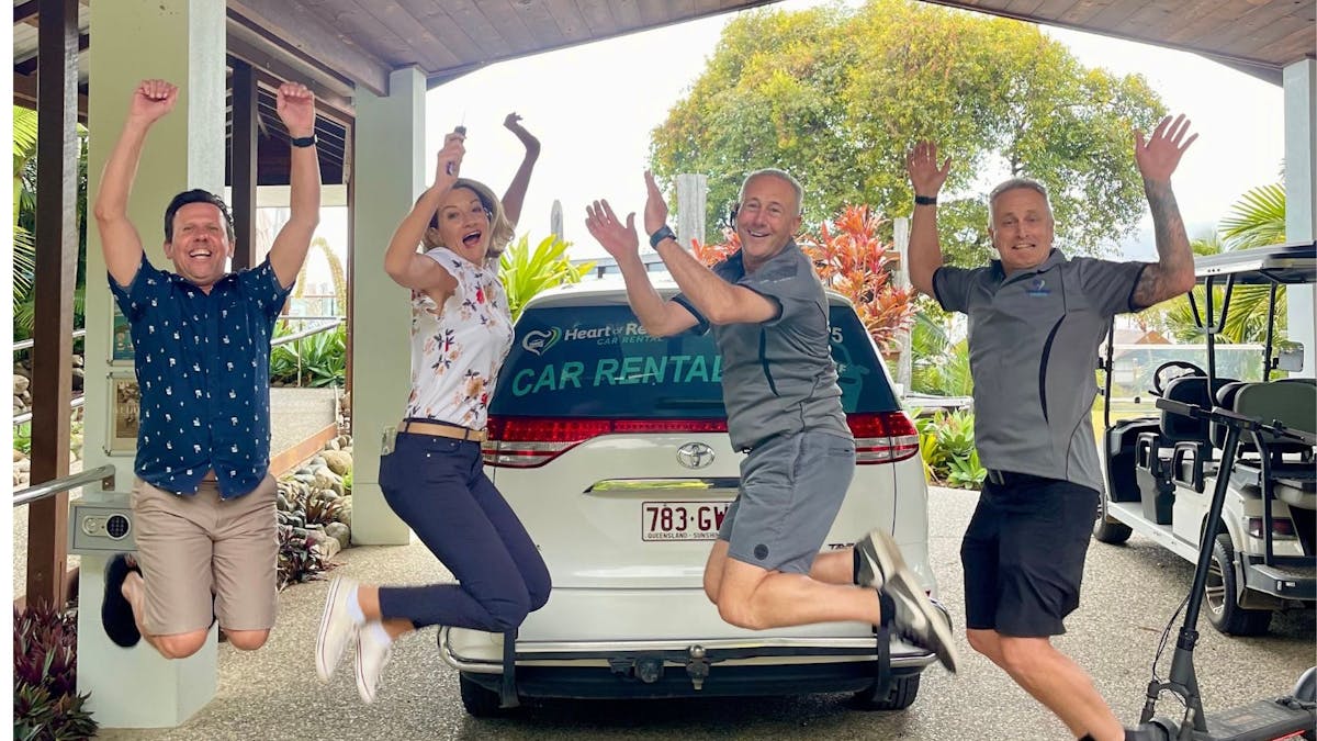Heart of Reef Car Rental Team and customers jumping in front of car hire