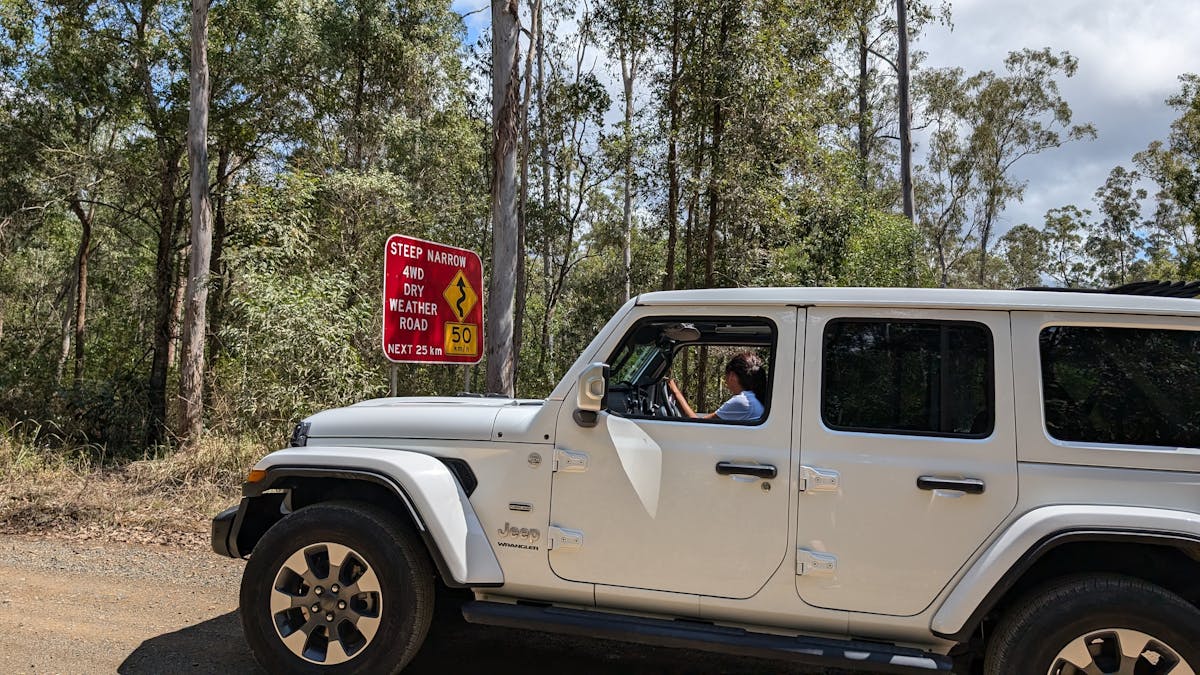 Sunny Jeeps, tour guide in the Jeep next to a sign explaining 4WD only, explore National Park