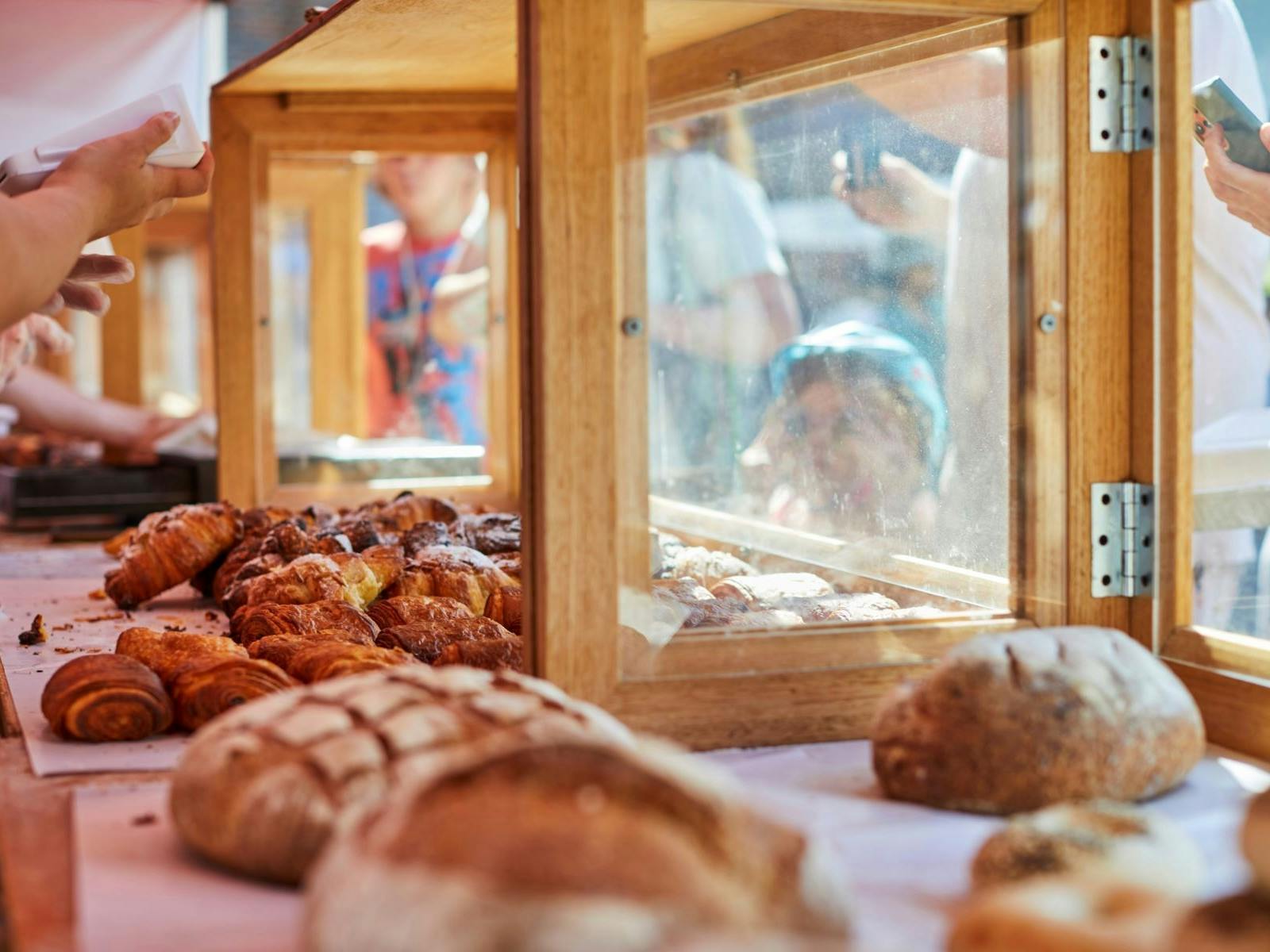 Freshly baked bread loafs in glass and wooden cabinet at market stall