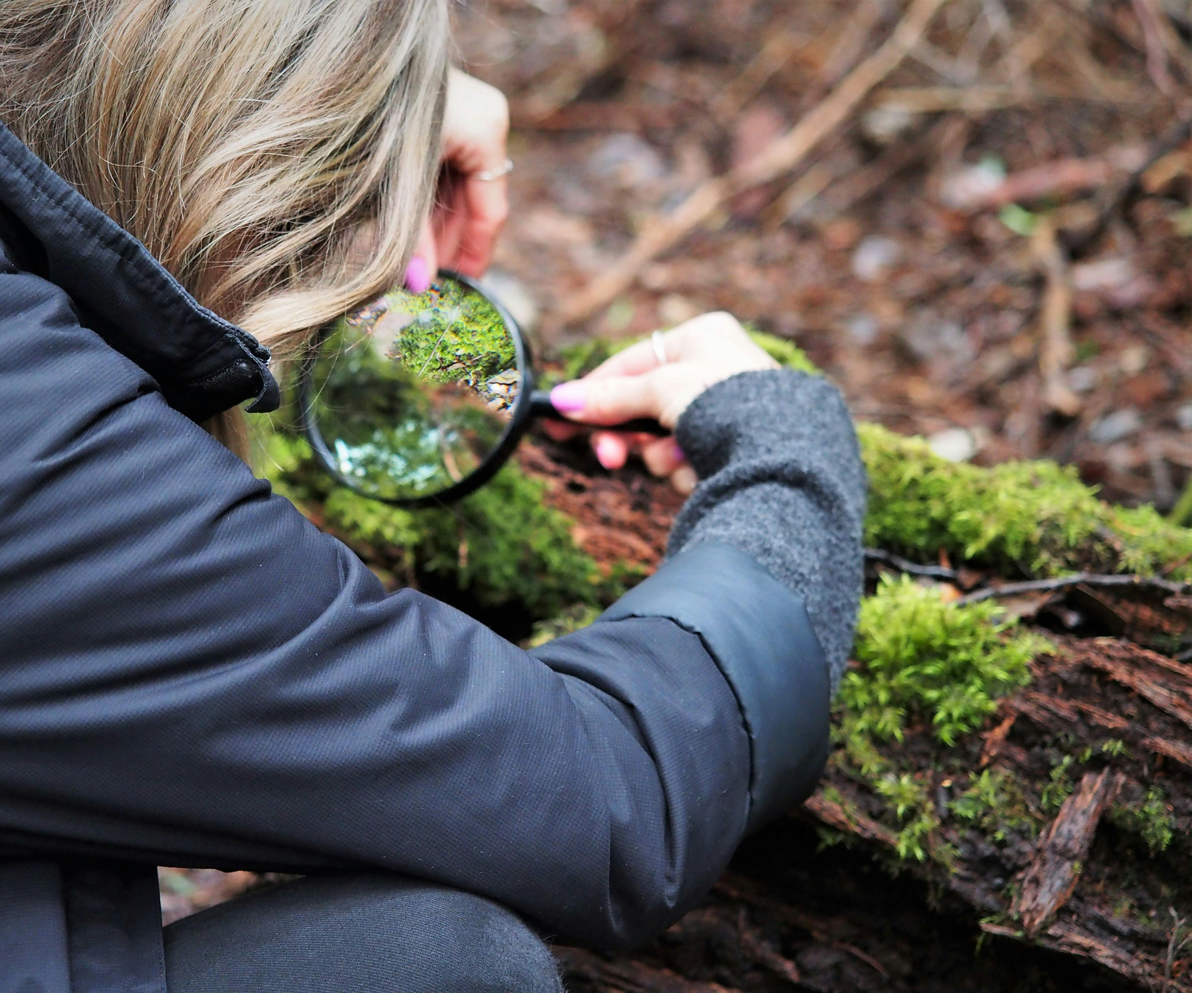 Girl look sat moss through a magnifying glass