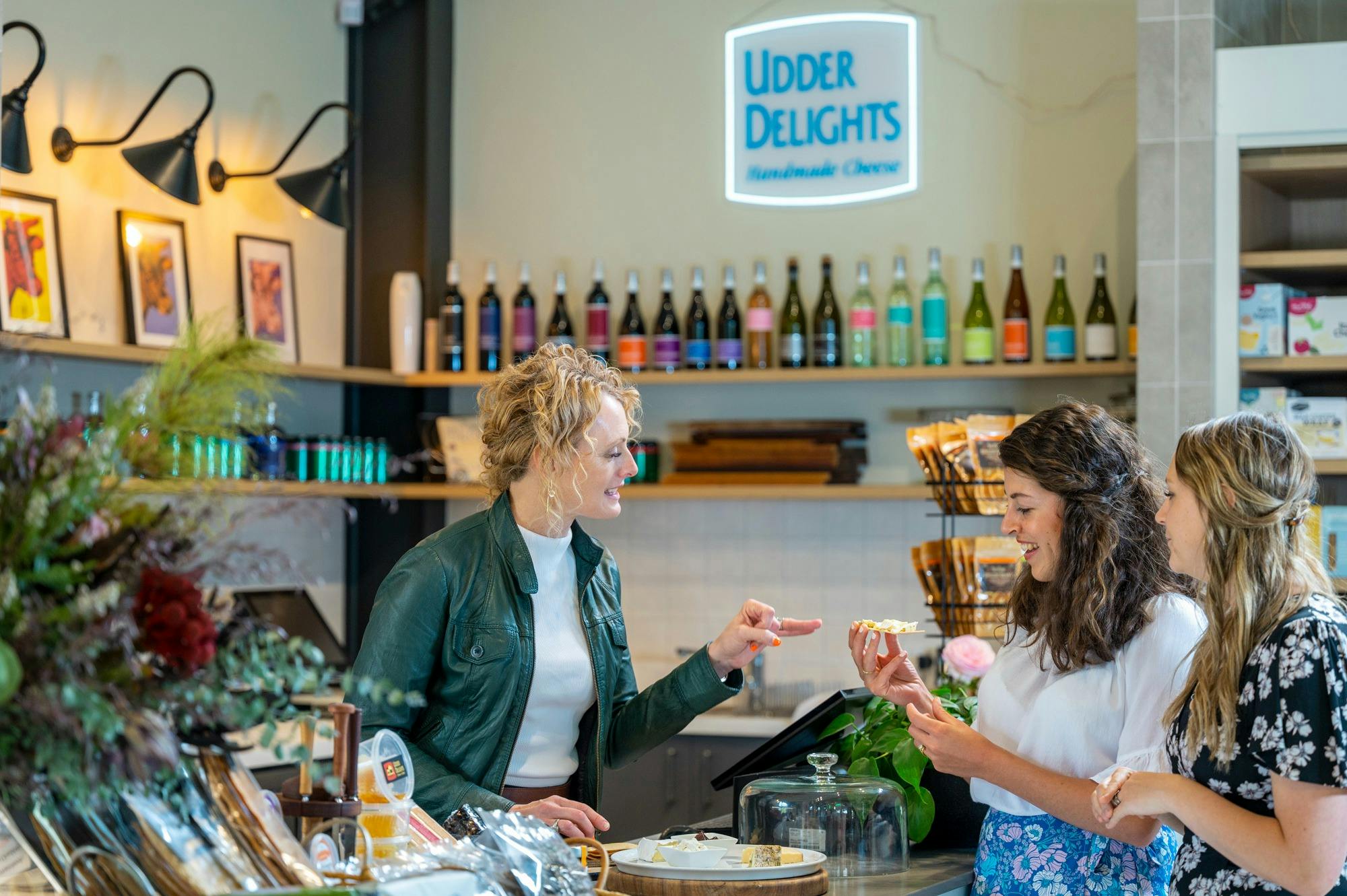 Cheese monger giving a cheese tasting to two customers