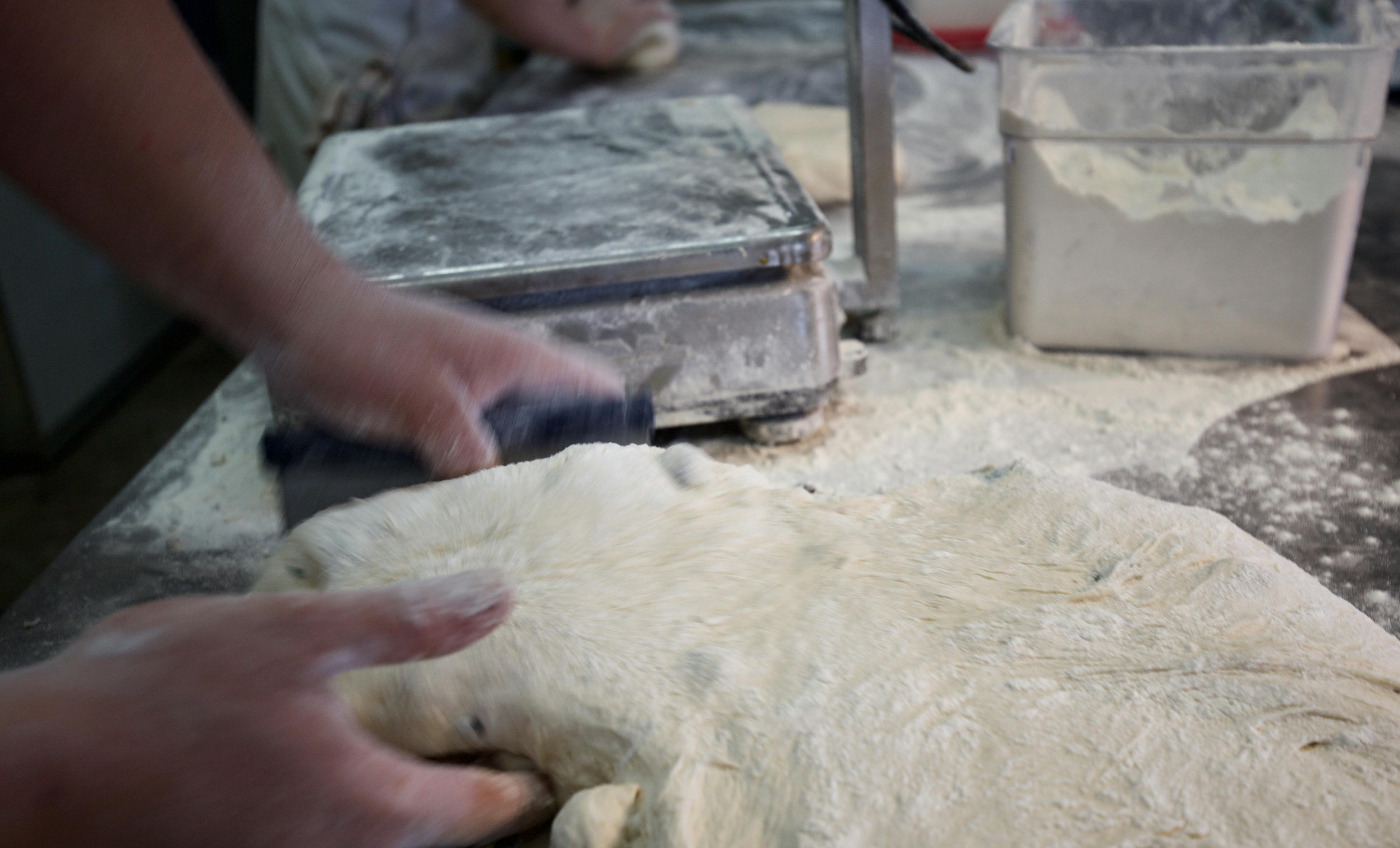 Bread dough on a bench with hands.