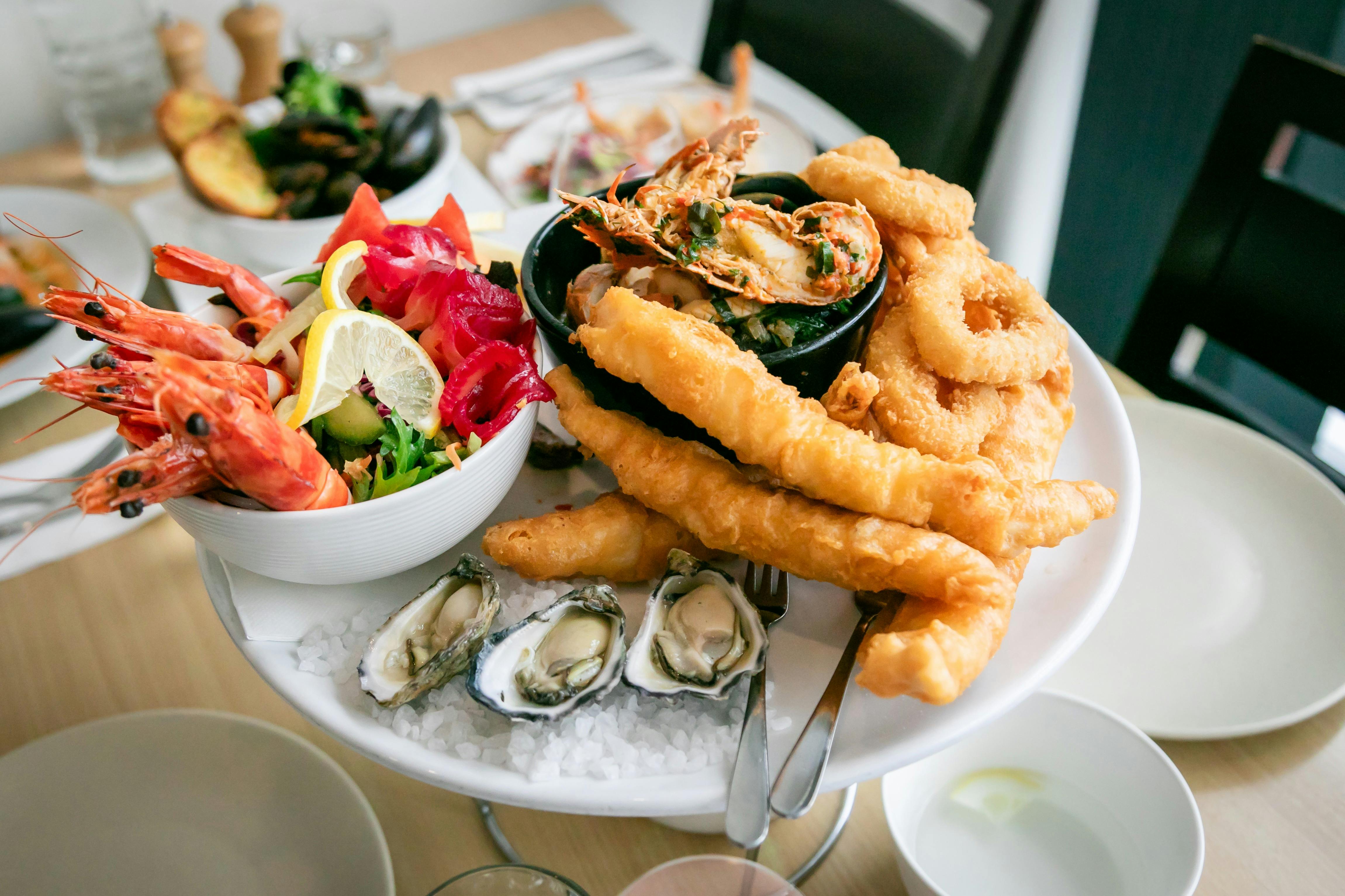 굴 새우 구운 생선과 튀긴 생선 오징어 가리비 등 신선한 현지 해산물 플래터입니다.