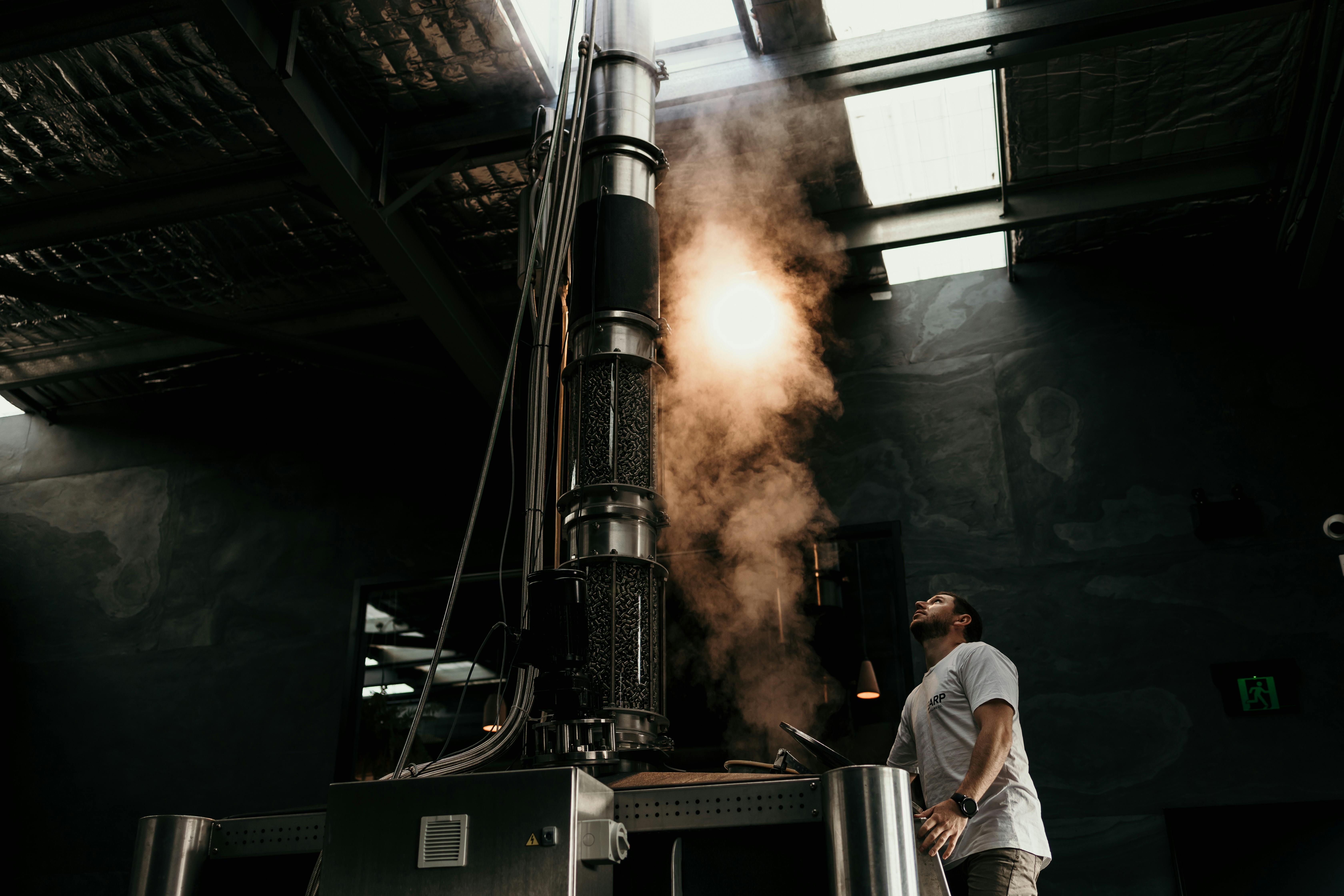 한 남자가 대형 스테인리스 스틸 스틸에 올라 증기가 나오는 것을 올려다봅니다.