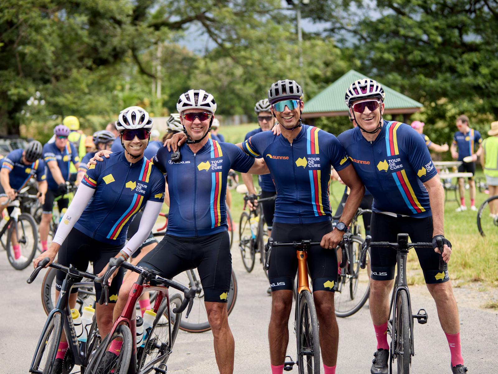 Four cyclists casually on bikes not riding inc. Ch7's Mark Beretta at the end of Signature Tour '25