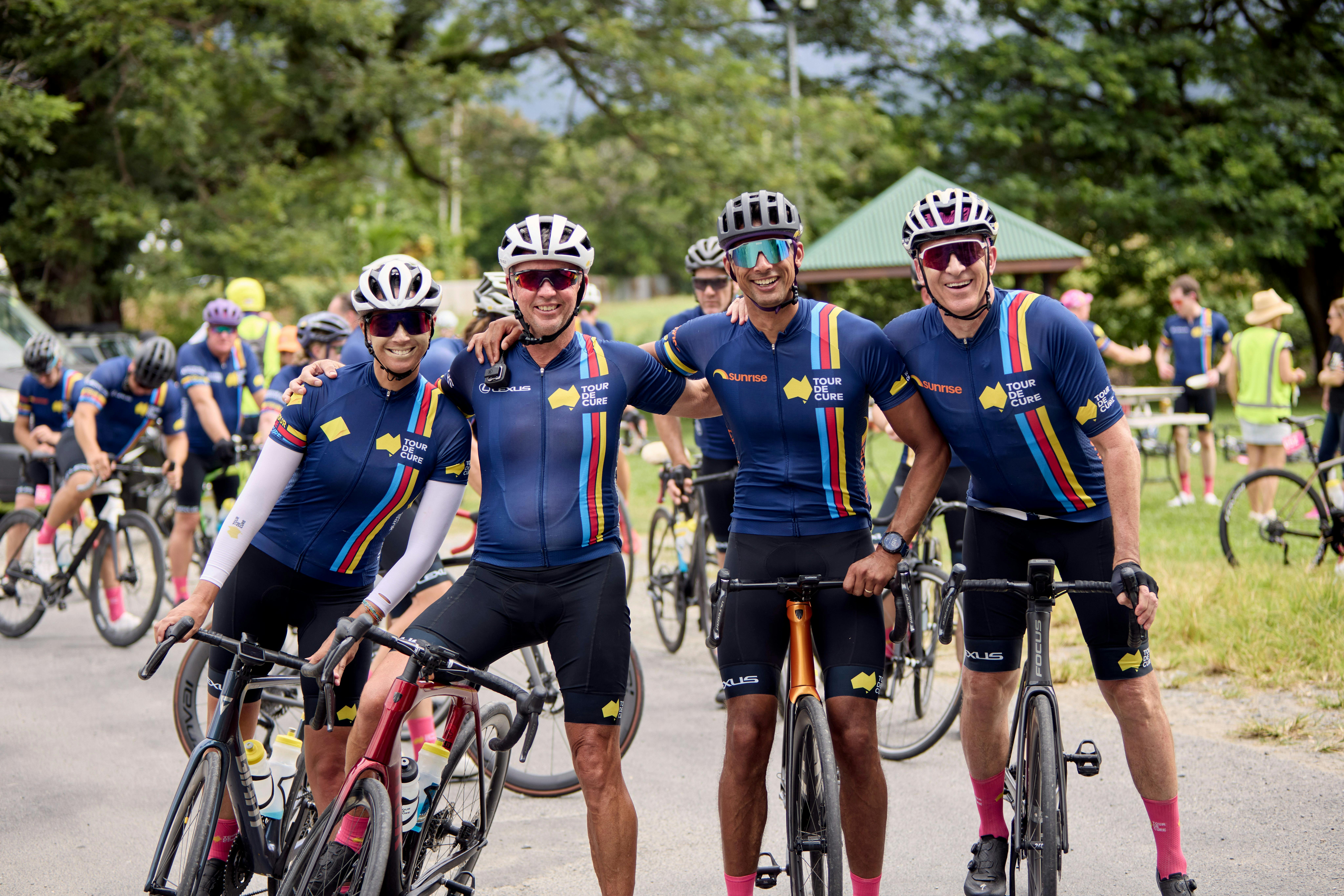 Four cyclists casually on bikes not riding inc. Ch7's Mark Beretta at the end of Signature Tour '25
