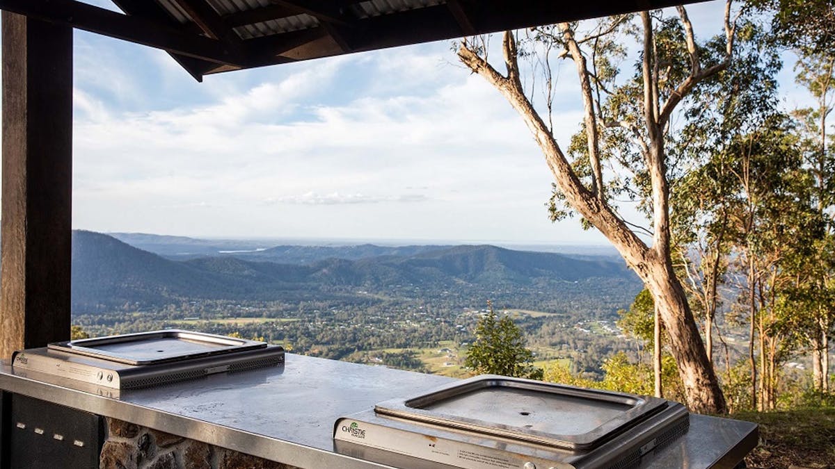 Two barbeques under a shelter with overlooking mountains